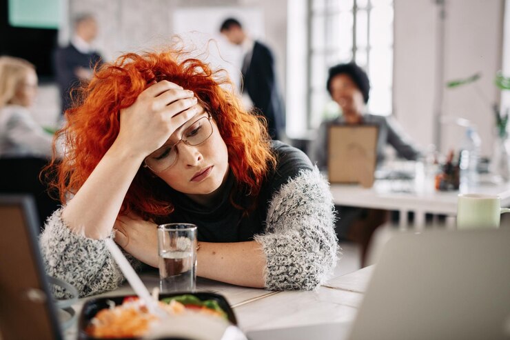 pensive-redhead-entrepreneur-feeling-tired-while-sitting-her-desk-office-there-are-people-background_637285-60